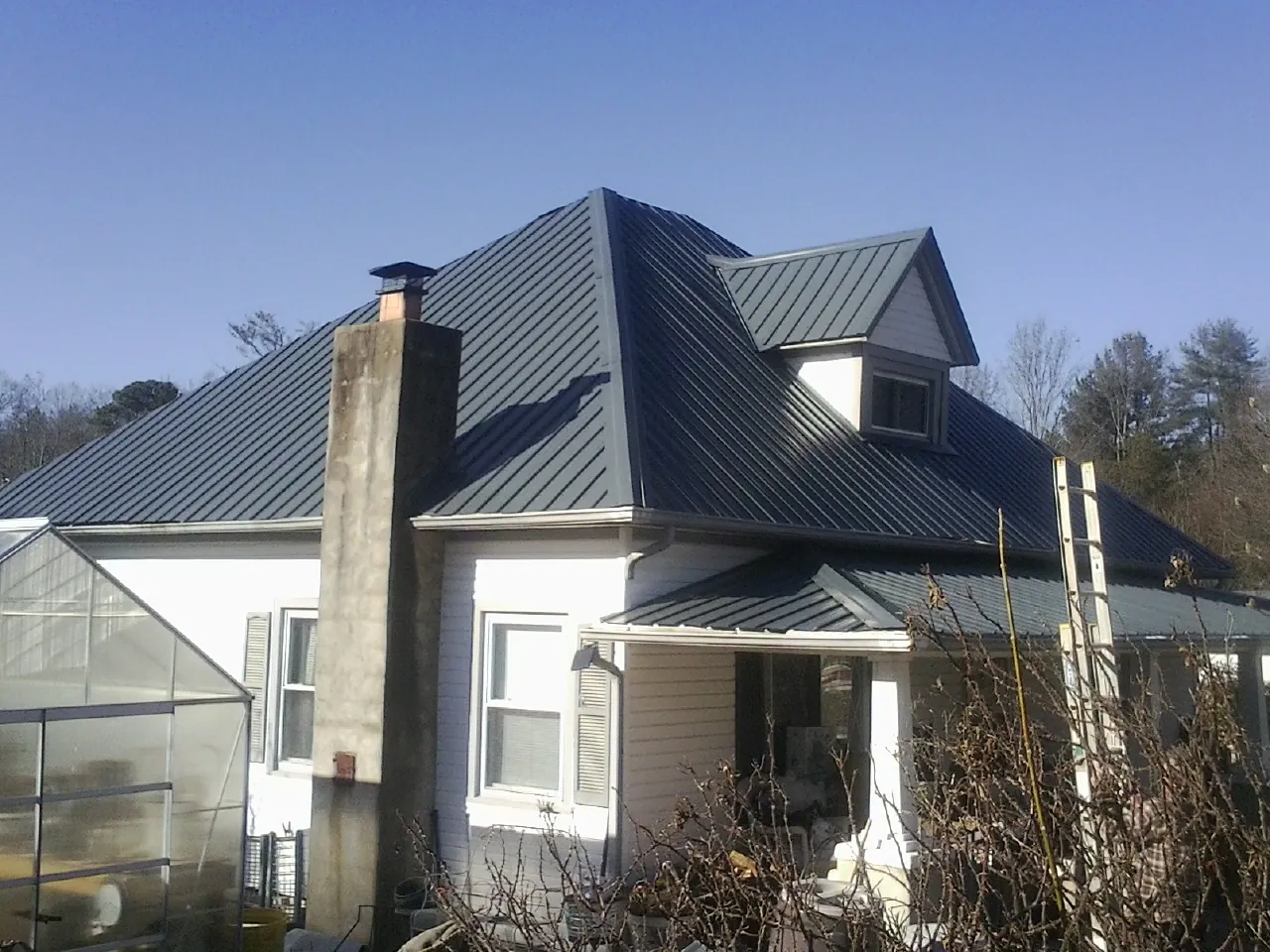 Dark blue standing seam metal roof on a white farmhouse with dormer — Slate & Tile Roof Repair by Roofing Brothers in Bear Lake