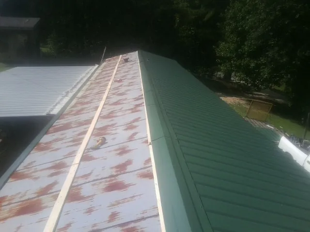Old rusted panels beside newly installed green metal roofing — Wind Damage Roof Repair by Roofing Brothers in Bear Lake