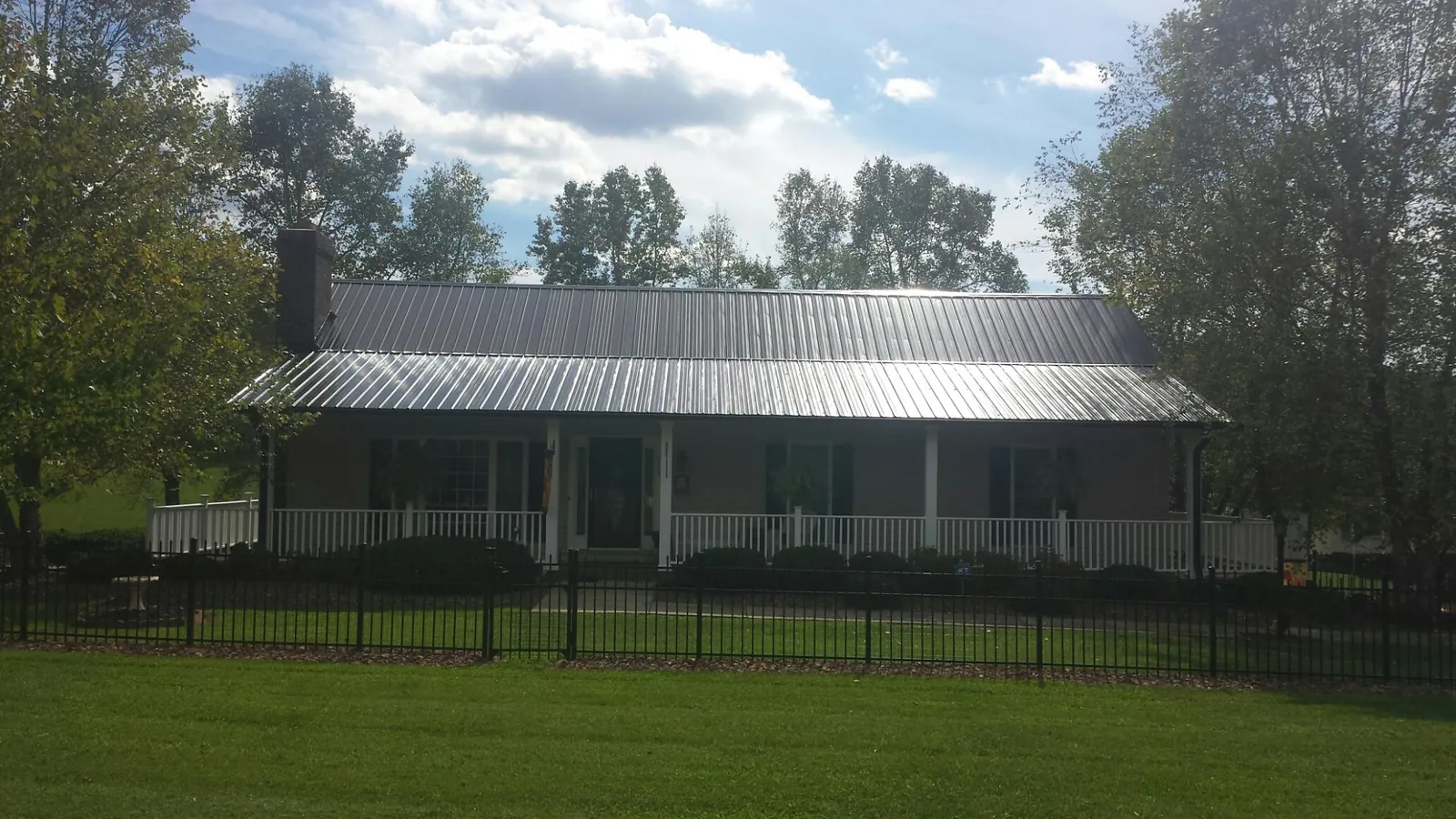 Gray metal roof on a brick ranch with a full width front porch — Gutter Guard Installation work by our crew in Bear Lake