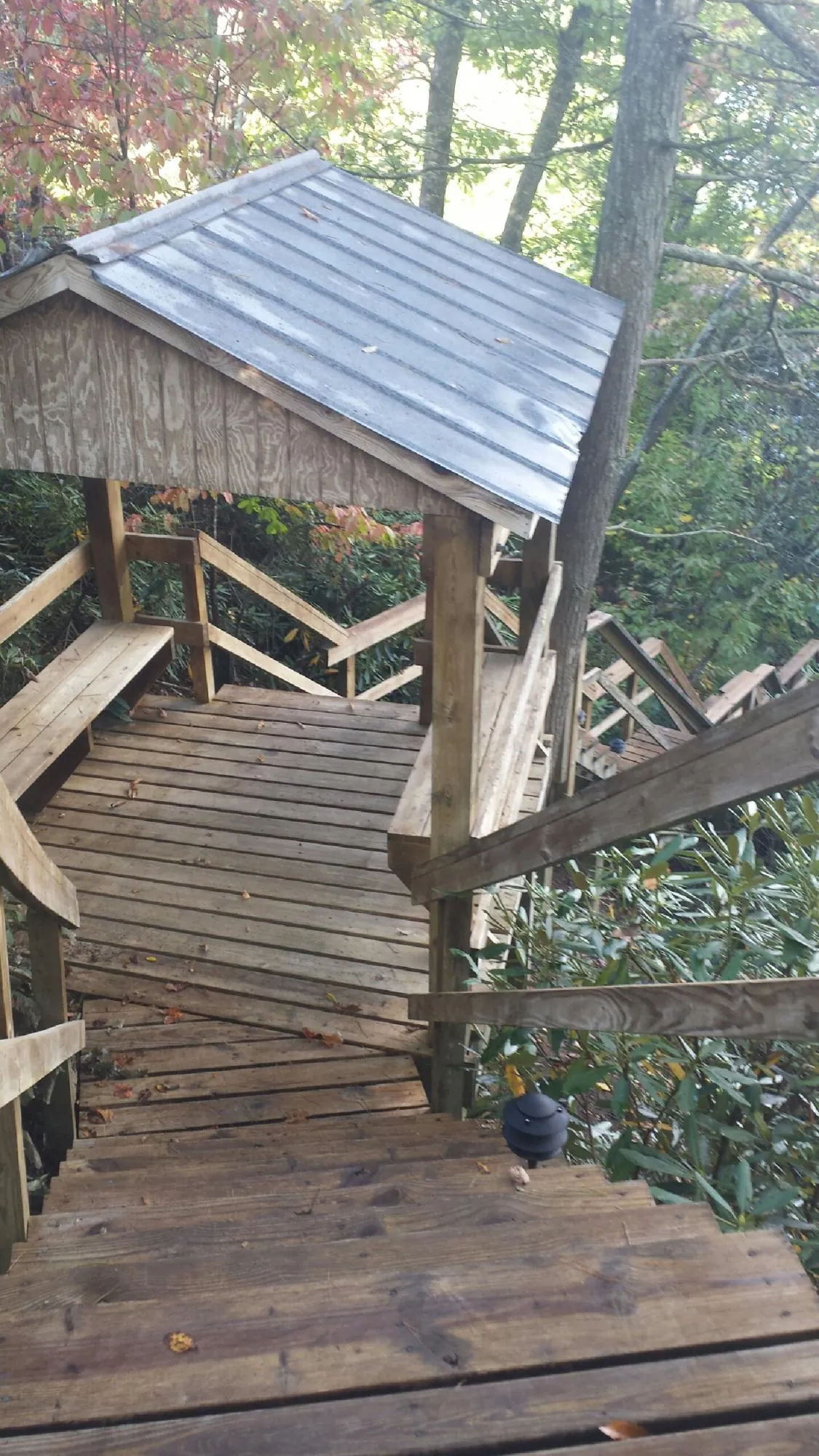 Metal roofed shelter over wooden steps on a wooded walkway — Skylight Repair & Installation work by our crew in Bear Lake