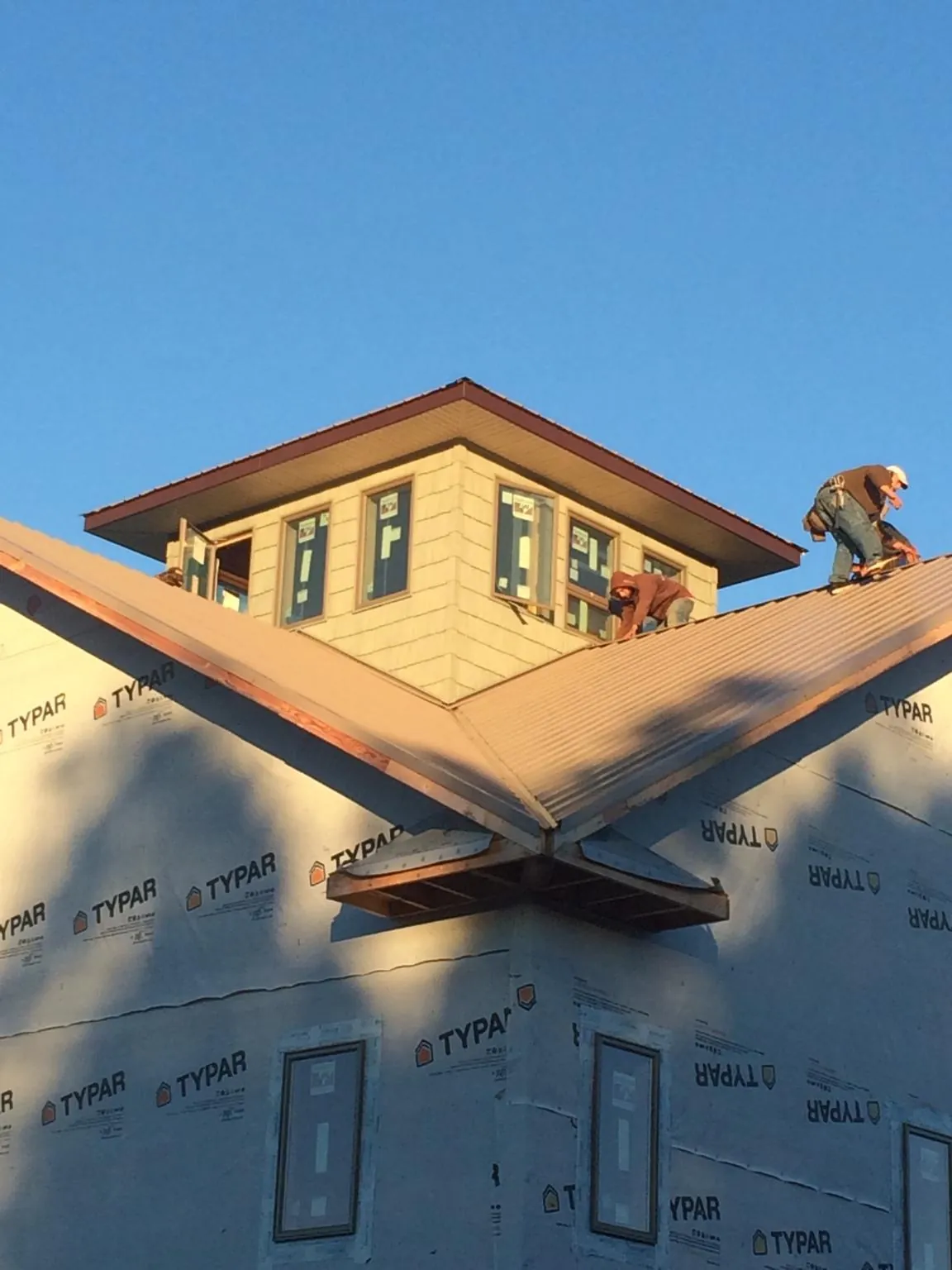 Roofers working around a rooftop cupola on a new metal roof at sunset — Roof Waterproofing in Bear Lake by Roofing Brothers